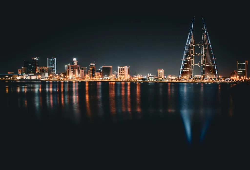 A city skyline at night with its lights reflected in the water