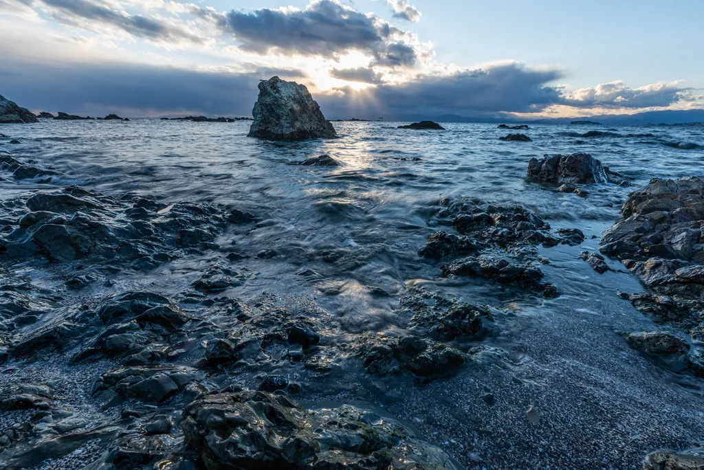 Dark rocks and tide pools along the sea under heavy clouds